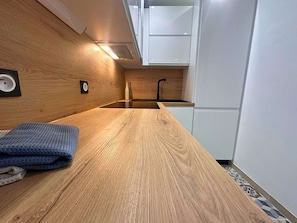 A compact kitchen with a wooden countertop, a sink, and white cabinetry. - Asteria by Pom, pkg, clim, wifi (Agde)
