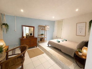 A bedroom with a bed, dresser, mirror, and a welcome sign.