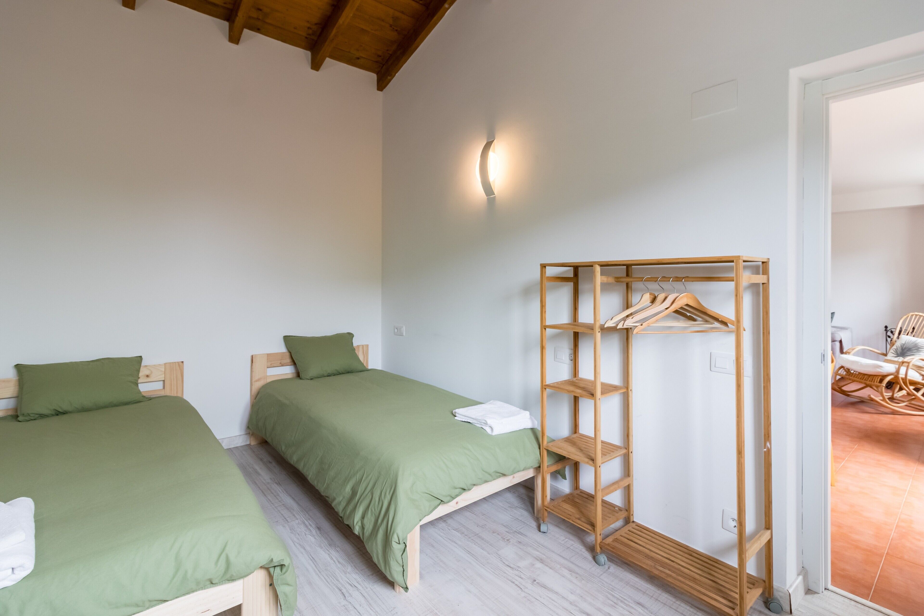 Une chambre avec deux lits, une armoire en bois et un luminaire.