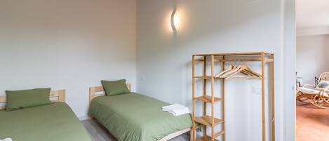 A bedroom with two beds, a wooden wardrobe, and a light fixture.