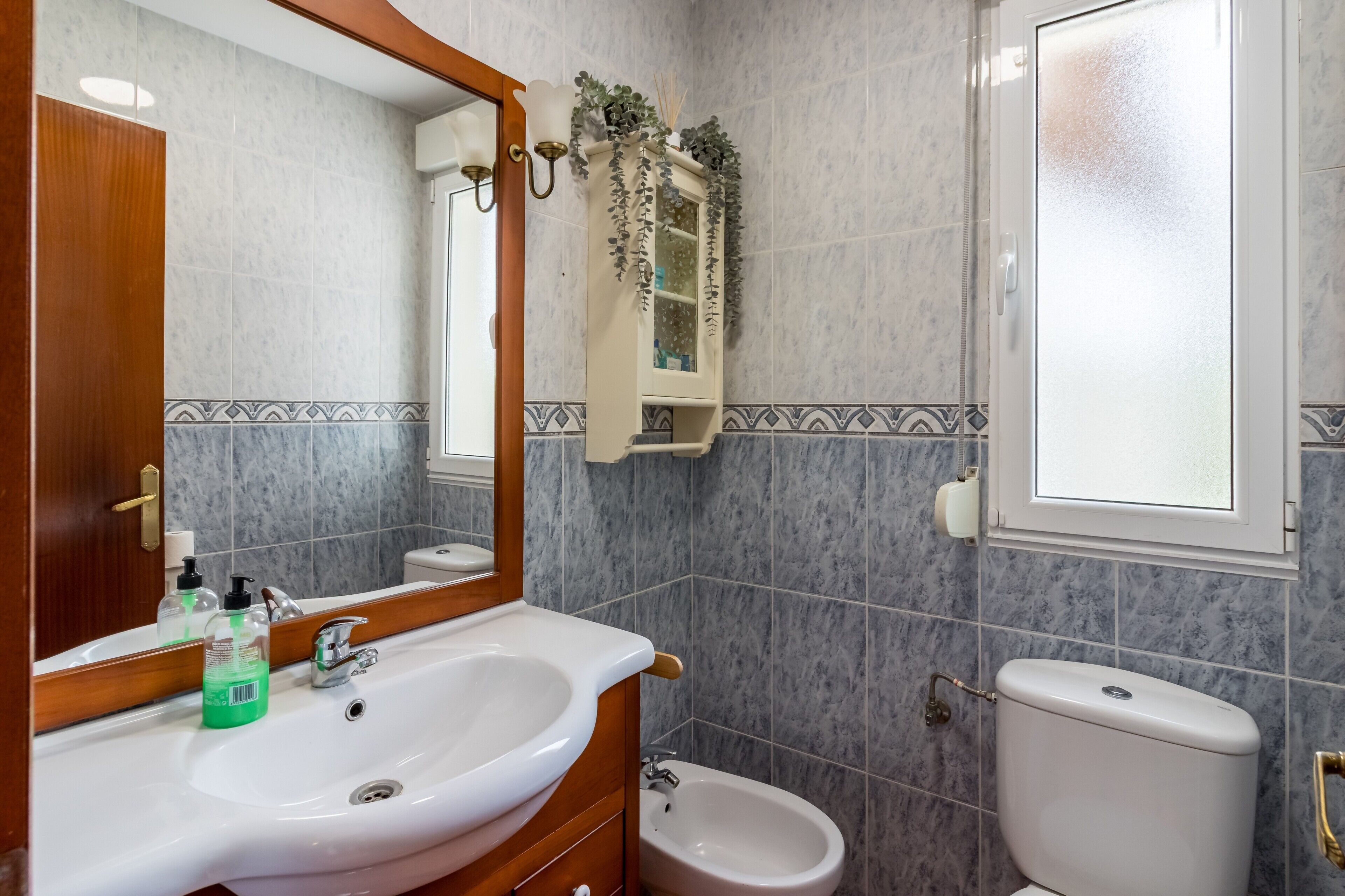 Une salle de bain avec un lavabo blanc, un miroir, des toilettes et un bidet.