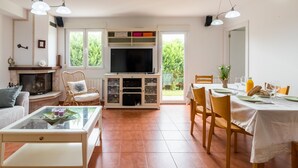 A living room with a fireplace, television, dining table, and chairs. - Casa Margarita in Rada (Rada)