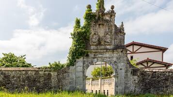 Un vieux portail en pierre, orné de sculptures complexes, et un bâtiment avec un toit recouvert de tuiles rouges en arrière-plan.