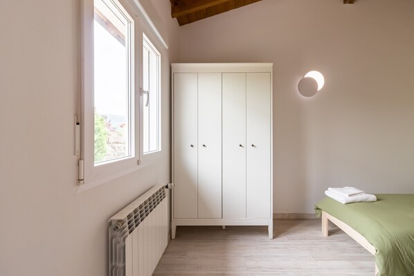 A bedroom with a bed, a wardrobe, a radiator, and a window.