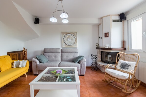 A living room with a sofa, a coffee table, a rocking chair, a fireplace, and a ceiling light fixture.