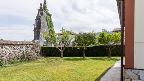 A stone wall, a grassy yard, and a pathway leading to a building. - Casa Margarita in Rada (Rada)