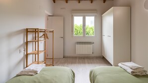 A room with two beds, a wooden wardrobe, a radiator, and a window with a view of greenery. - Casa Margarita in Rada (Rada)