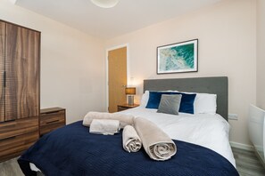 Ein Hotelzimmer mit einem Bett, einem Kleiderschrank, einem Gemälde und einem Nachttisch.
