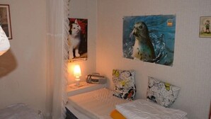 A bedroom with a bed, a nightstand, a lamp, and two wall-mounted paintings. - Vacation home on the lake with rowing boat! (Nye)