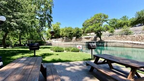 A backyard with a swimming pool, picnic tables, and a 'NO DIVING' sign. - Comal River Condo 307 (New Braunfels)
