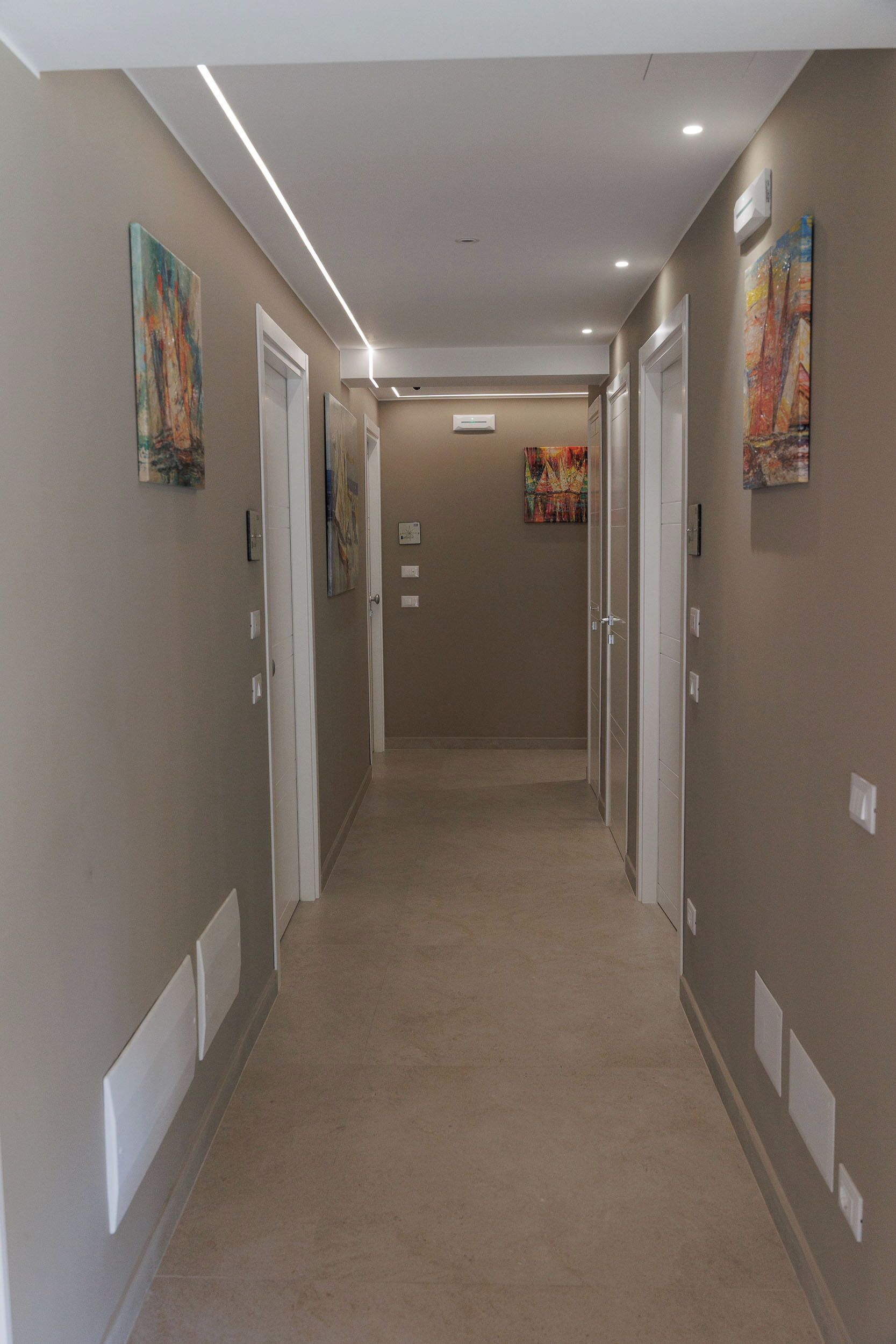 A hallway with beige walls, white doors, and recessed lighting.