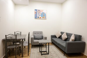 Un salon moderne avec une table à manger, un canapé gris et un tableau accroché au mur.