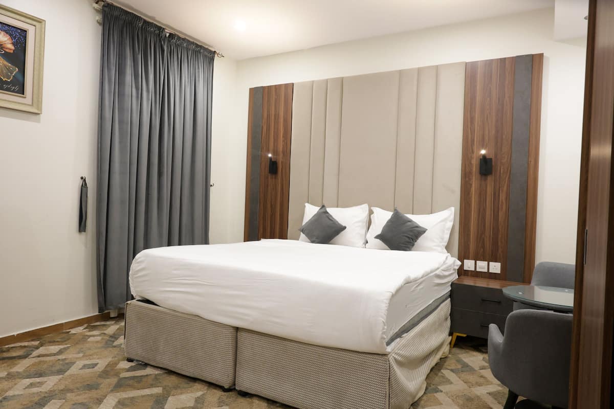 Una habitación de hotel con una cama grande, un escritorio pequeño y un armario de diseño moderno.