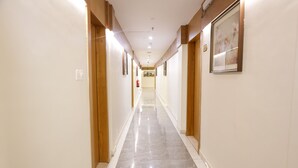 A long, narrow hallway with wooden doors on either side and a marble floor. - Durrat Al Aziziyah Serviced Apartments (Madinah)