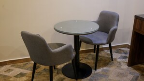 A room with a round glass table and two grey chairs. - Durrat Al Aziziyah Serviced Apartments (Madinah)