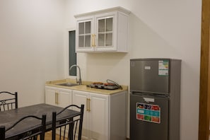 Une cuisine avec des meubles blancs, un réfrigérateur en acier inoxydable, un évier et une table à manger avec des chaises.