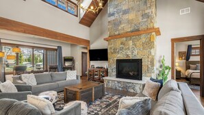 A spacious living room with a stone fireplace, a large flat-screen TV, and a cozy seating area with sofas and a coffee table. - Lucky Star Lodge | Pool & Hot Tub | Fire Pit (Durango)