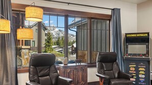 A room with two leather chairs, a wooden cabinet, and a large window with a view of mountains. - Lucky Star Lodge | Pool & Hot Tub | Fire Pit (Durango)