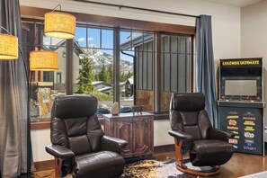 A room with two leather chairs, a wooden cabinet, and a large window with a view of mountains. - Lucky Star Lodge | Pool & Hot Tub | Fire Pit (Durango)