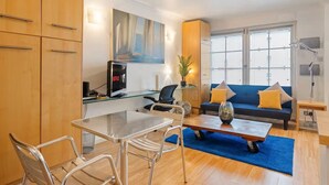 A modern living room with a sofa, coffee table, and dining area. - Charming Mews House Near King's Cross (London)