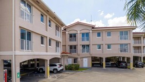 A multi-story building with a parking garage, multiple balconies, and a clear sky. - Triangle Suites LLC (Hialeah)