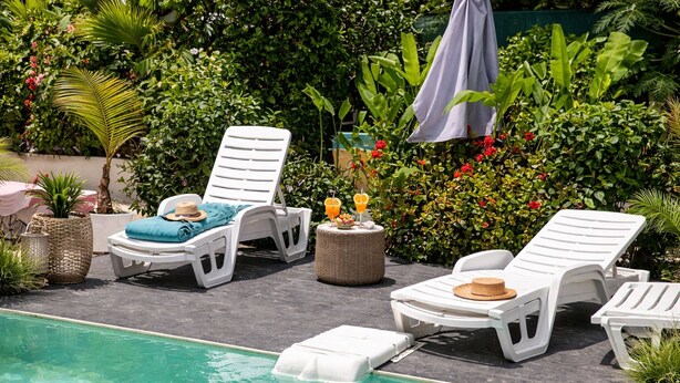 A poolside area with lounge chairs, a small table, and a potted plant.