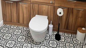 Ein Badezimmer mit einem weißen Waschbecken, einem runden Spiegel, einer Toilette und einem Musterfußboden.