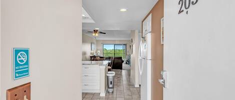 A hallway with a 'NO SMOKING' sign, a number '205' on the wall, a ceiling fan, and a view to a balcony.