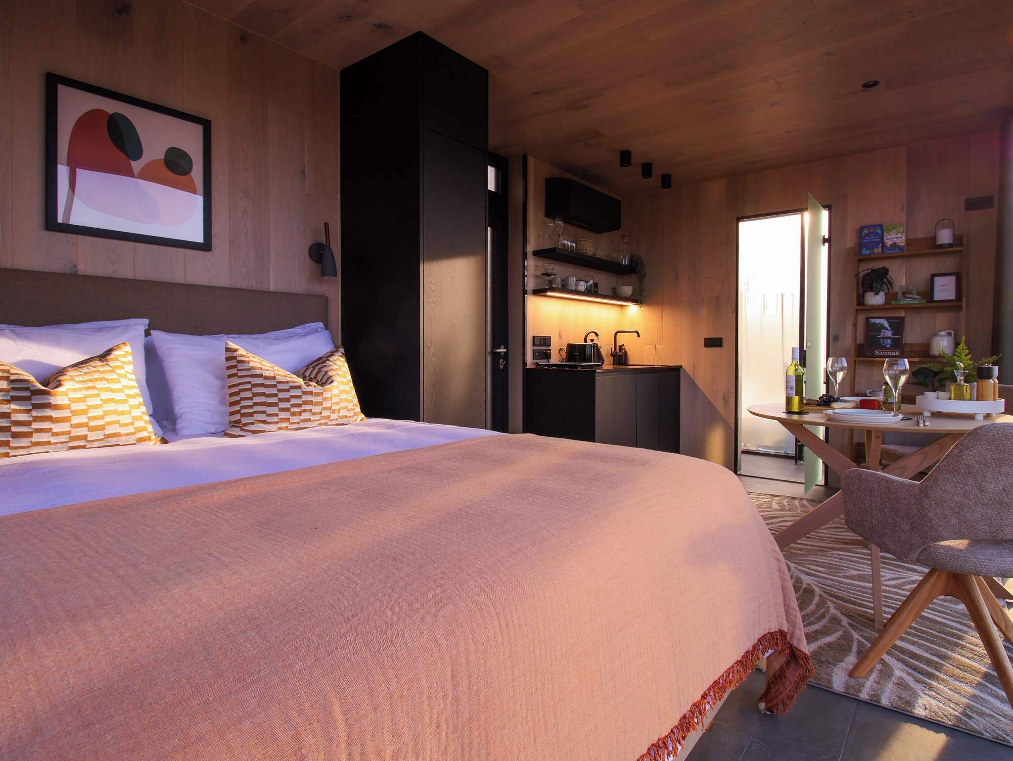 Ein modernes Schlafzimmer mit einem großen Bett, einer kleinen Küchenzeile und einem Essbereich.