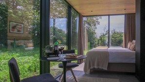 Una stanza con un letto, un tavolo da pranzo con sedie e vista sul verde circostante.