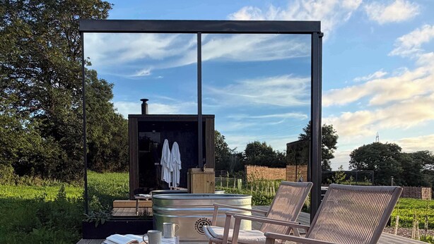 Una terrazza esterna con poltrone da relax, un tavolo con un libro e una tazza, e una sauna.