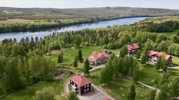 A large property with multiple buildings, a lake, and forested hills. - Kronlund Kursgård (Vindeln)