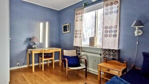 A room with a wooden table, a chair, a radiator, and a window with curtains. - Kronlund Kursgård (Vindeln)