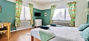 Une chambre avec deux lits, un bureau, une commode et un radiateur.