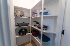 Una cucina con pensili bianchi, una macchina per il caffè, una cuociriso e un frullatore sugli scaffali.