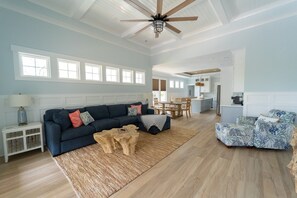 A spacious living room with a dark blue sofa, a wooden coffee table, and a patterned armchair. - Happy Tides Hideaway/NEW!/Pool/Kids Adventure Room (Oak Island)