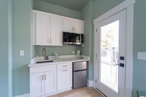 A kitchen with white cabinets, a stainless steel dishwasher, and a microwave. - Happy Tides Hideaway/NEW!/Pool/Kids Adventure Room (Oak Island)