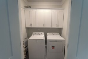 Una lavanderia con due lavatrici e asciugatrici Maytag, pensili bianchi sopra e un termosifone a sinistra.