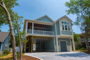 A two-story house with a covered front porch and a second-story balcony. - Happy Tides Hideaway/NEW!/Pool/Kids Adventure Room (Oak Island)