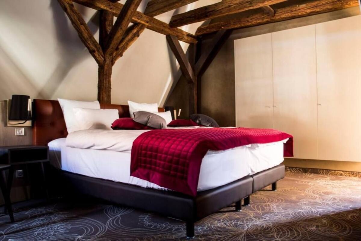 Une chambre à coucher avec un lit, des oreillers, une table de chevet et une lampe fixée au mur.