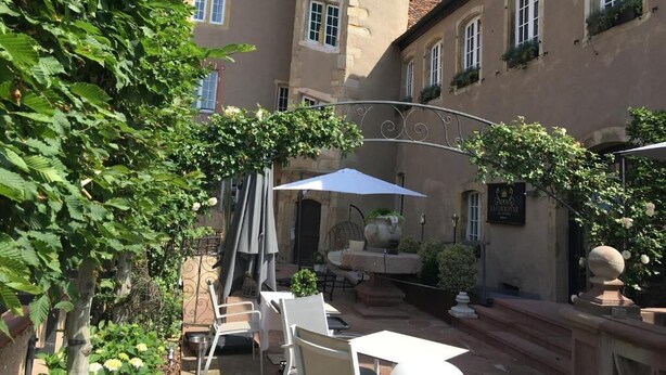 A courtyard with outdoor seating, a fountain, and a building with multiple windows. - Hotel Restaurant l'Orchidée (Ensisheim)
