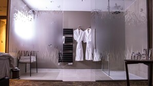 A modern bathroom with a glass partition, white towels, and a patterned carpet. - Hotel Restaurant l'Orchidée (Ensisheim)