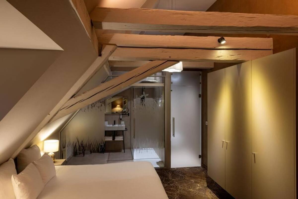 Une chambre à coucher comprenant un lit, une table de chevet, un miroir et une salle de bain avec un lavabo et un miroir.