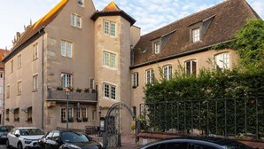 A historic building with a prominent corner, a gated entrance, and a visible balcony with plants. - Hotel Restaurant l'Orchidée (Ensisheim)