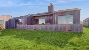 Una casa moderna con fachada de madera, ventanas amplias y una chimenea.