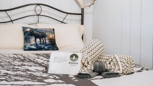 A bed with a patterned bedspread, a pillow with a moose image, a folded blanket, and a sign with the text 'BEAUSITE Tourism'. - Nature & Wildlife Escape | Alfred Shack (Frampton)