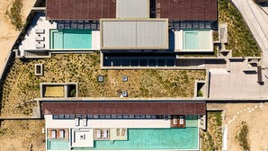 A modern resort with multiple swimming pools, a large building with a flat roof, and a sandy landscape. - Sky Resort in Mykonos (Mykonos)
