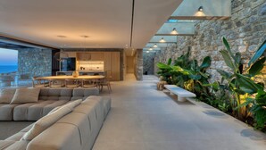 A modern interior with a stone wall, a dining area, and a seating area. - Sky Resort in Mykonos (Mykonos)