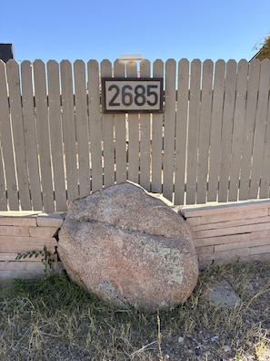 A wooden fence with a house number sign.