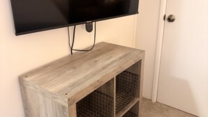 A television mounted on a wooden console with wire shelves below. - Fine Studio Nine @ Rustic Ridge in Granite Dells (Prescott)
